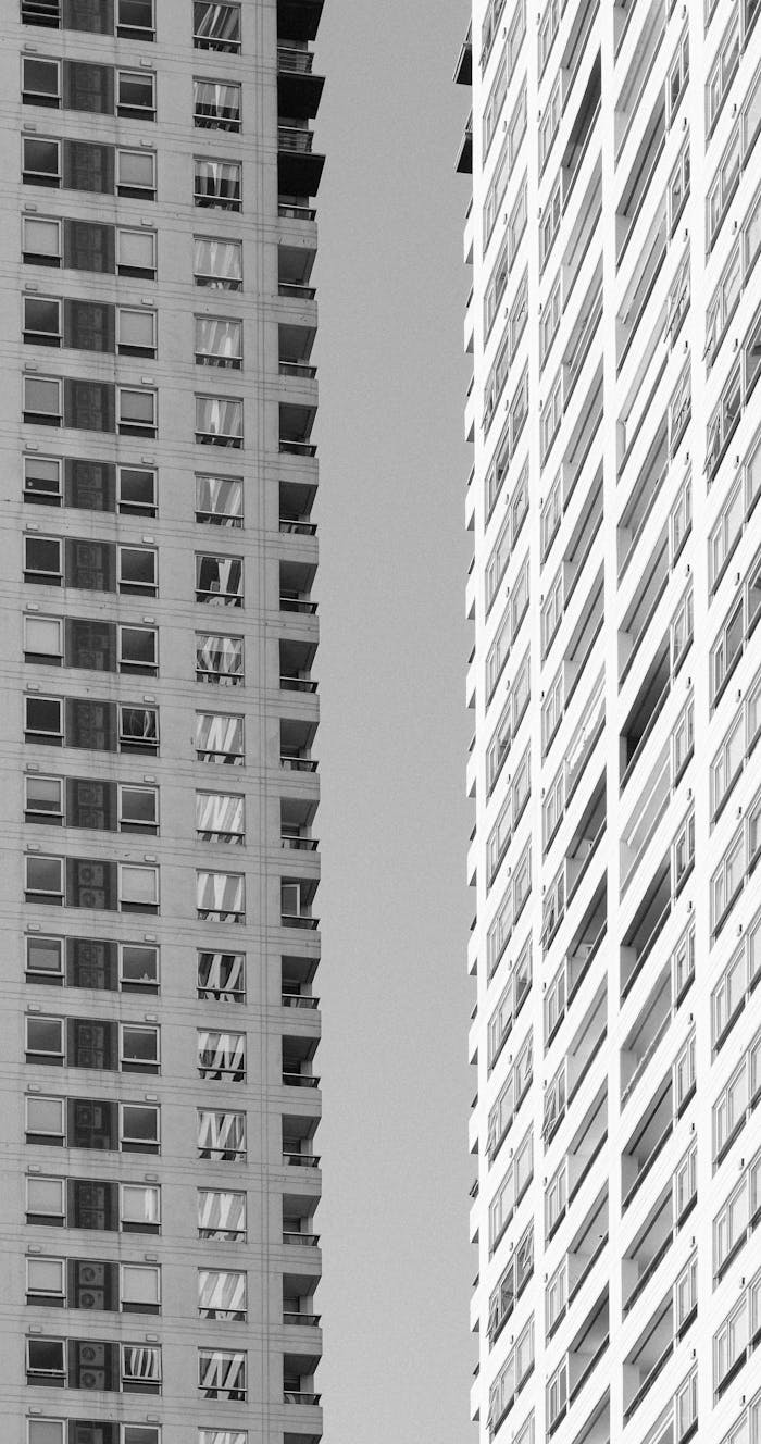Grayscale photo showcasing two modern high-rises with vertical design focus.